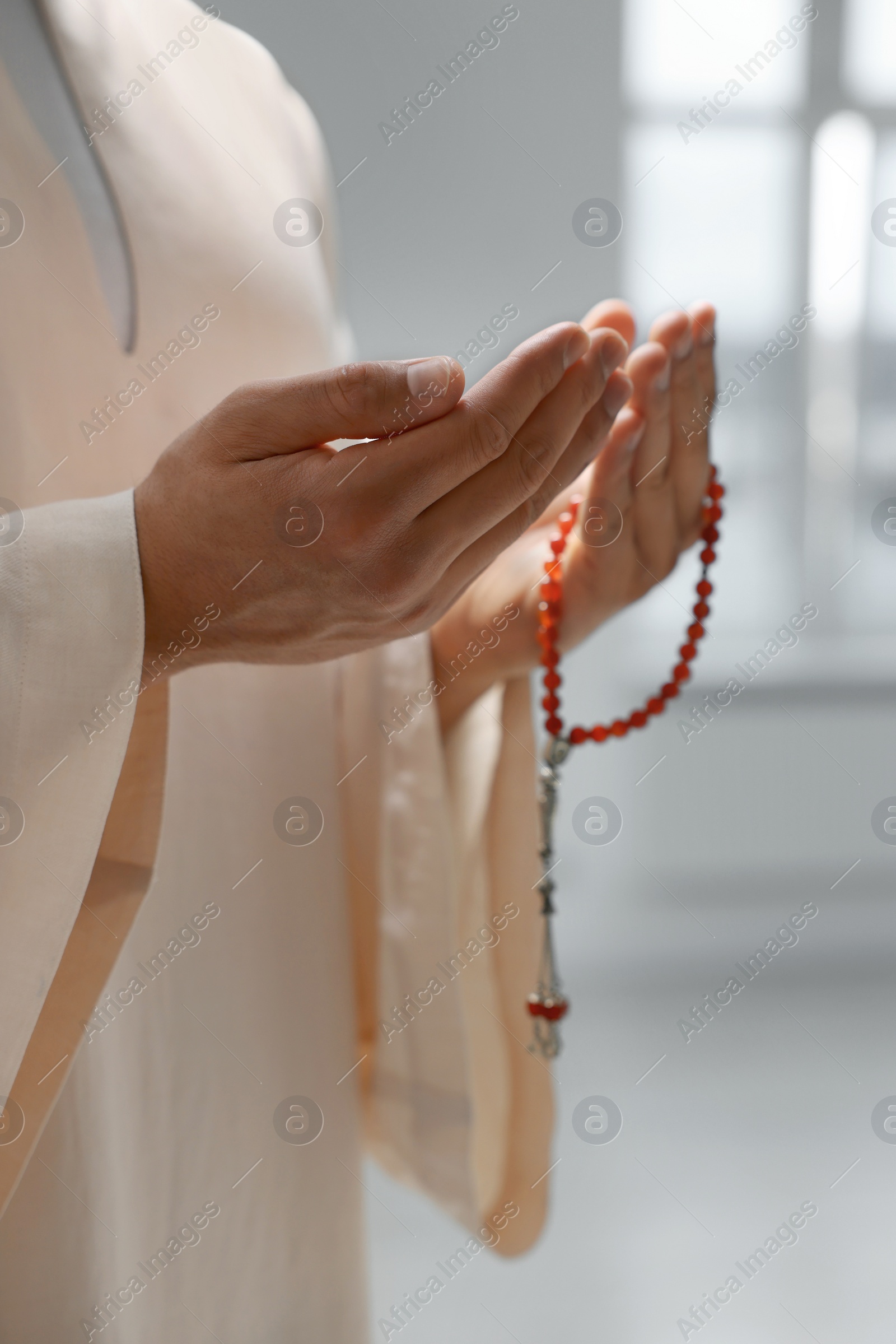 Photo of Muslim man with misbaha praying indoors, closeup