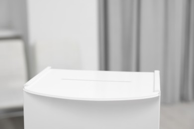 Photo of White ballot box on blurred background, closeup