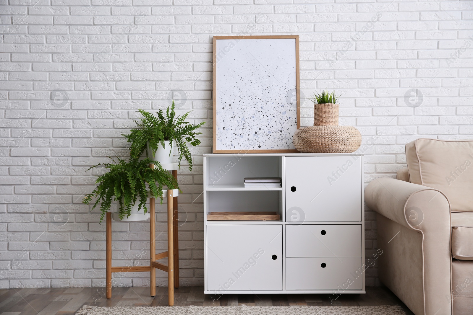 Photo of Modern white cabinet near brick wall in room. Interior design