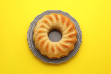 Photo of One tasty sponge cake on yellow background, top view