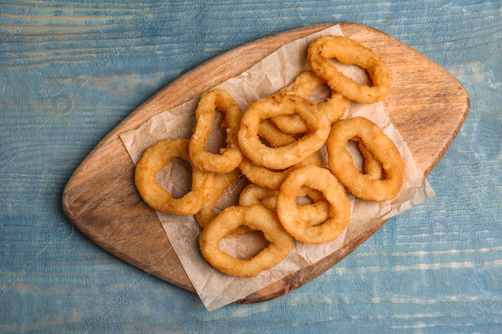 Photo of Fried onion rings served on blue wooden table, top view
