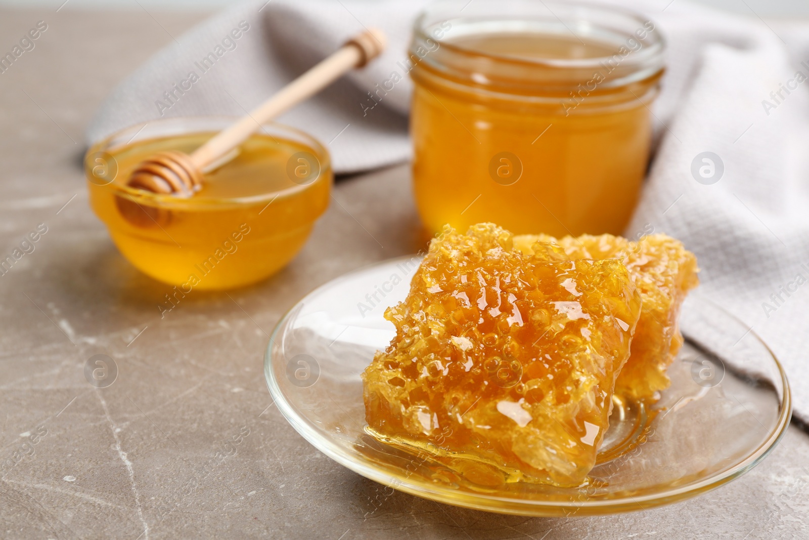 Photo of Tasty honey and combs on brown marble table, closeup