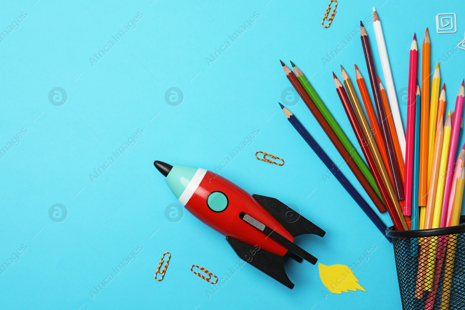 Photo of Bright toy rocket and school supplies on light blue background, flat lay. Space for text