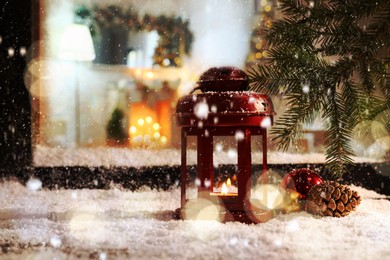 Image of Snow falling onto window sill with Christmas lantern outdoors 