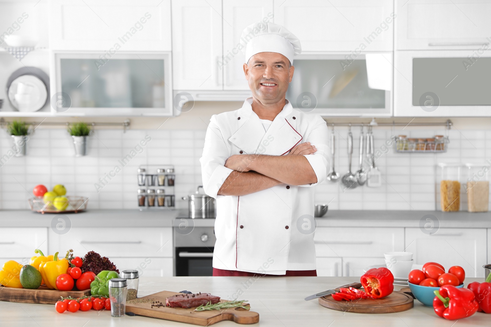 Photo of Professional male chef standing near table in kitchen