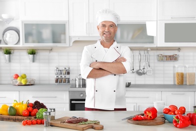 Professional male chef standing near table in kitchen