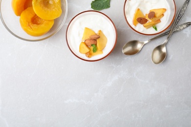 Photo of Tasty peach dessert with yogurt served on light table, flat lay. Space for text