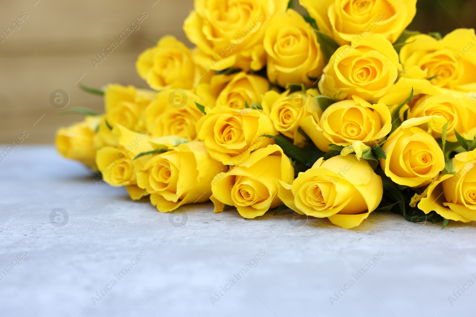 Photo of Beautiful bouquet of yellow roses on light table