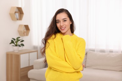 Beautiful young woman in stylish warm sweater at home