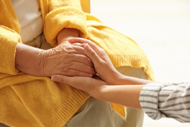 Photo of Helping hands on light background, closeup. Elderly care concept