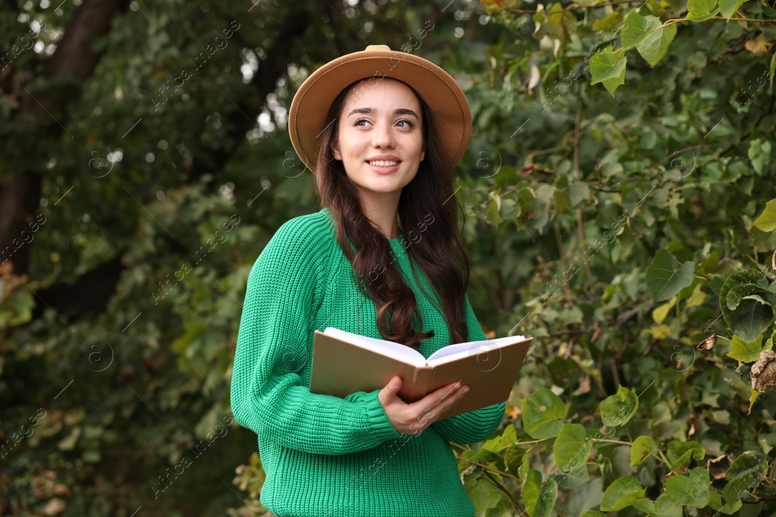 Photo of Beautiful young woman in stylish warm sweater reading book outdoors