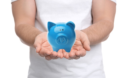 Young man holding piggy bank on white background, closeup 