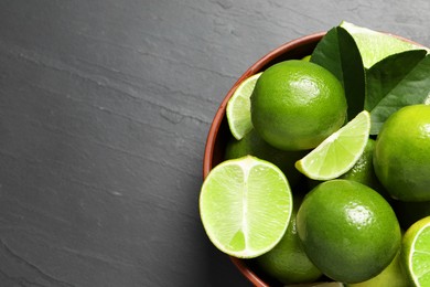 Photo of Fresh ripe limes in bowl on black table, top view. Space for text