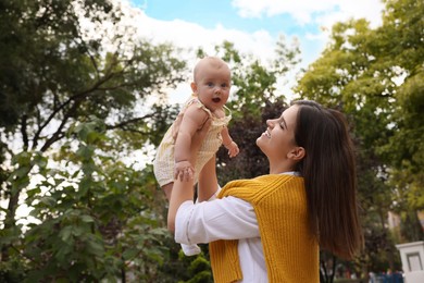 Happy mother with adorable baby walking in park on sunny day, space for text