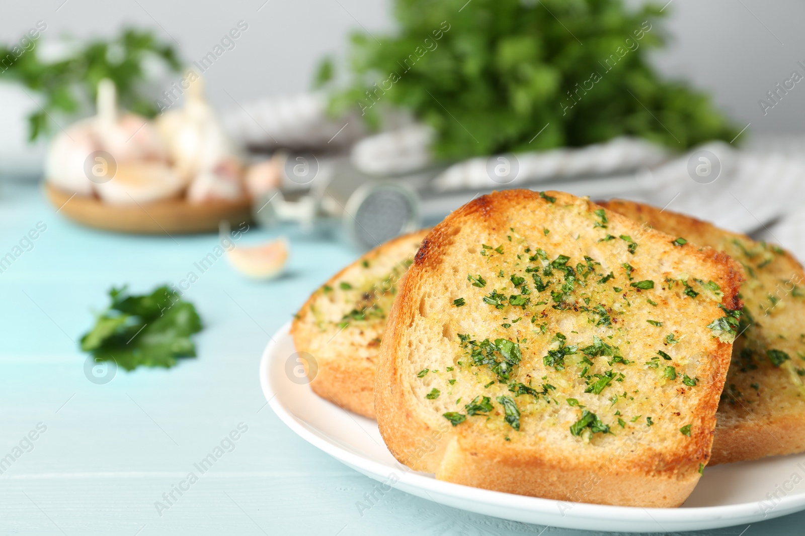 Photo of Slices of toasted bread with garlic and herbs on blue wooden table, closeup. Space for text