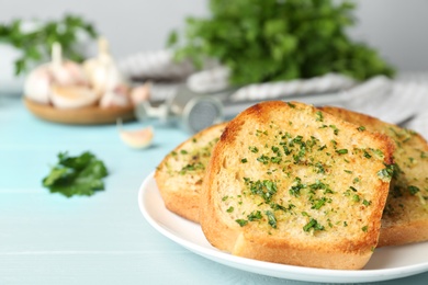 Photo of Slices of toasted bread with garlic and herbs on blue wooden table, closeup. Space for text