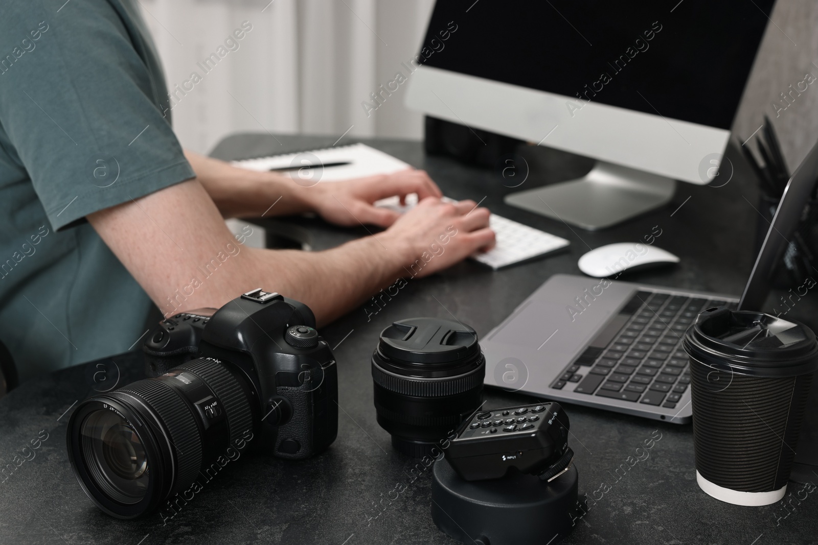 Photo of Camera on dark table, closeup. Photographer working with computer indoors, selective focus