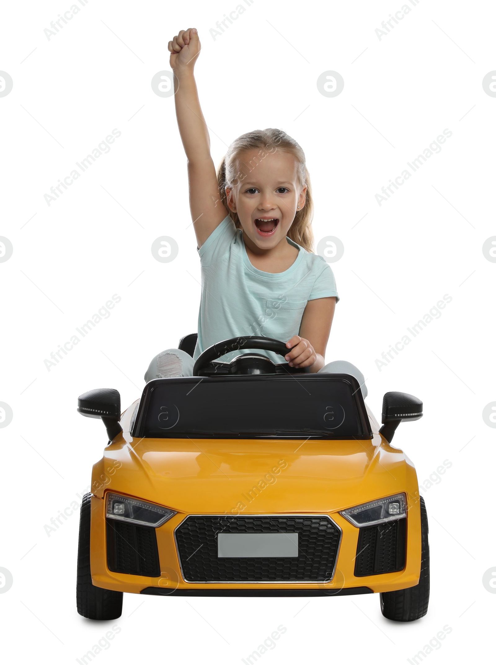 Photo of Cute little girl driving children's electric toy car on white background