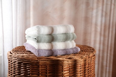 Stacked soft towels on rattan laundry basket indoors