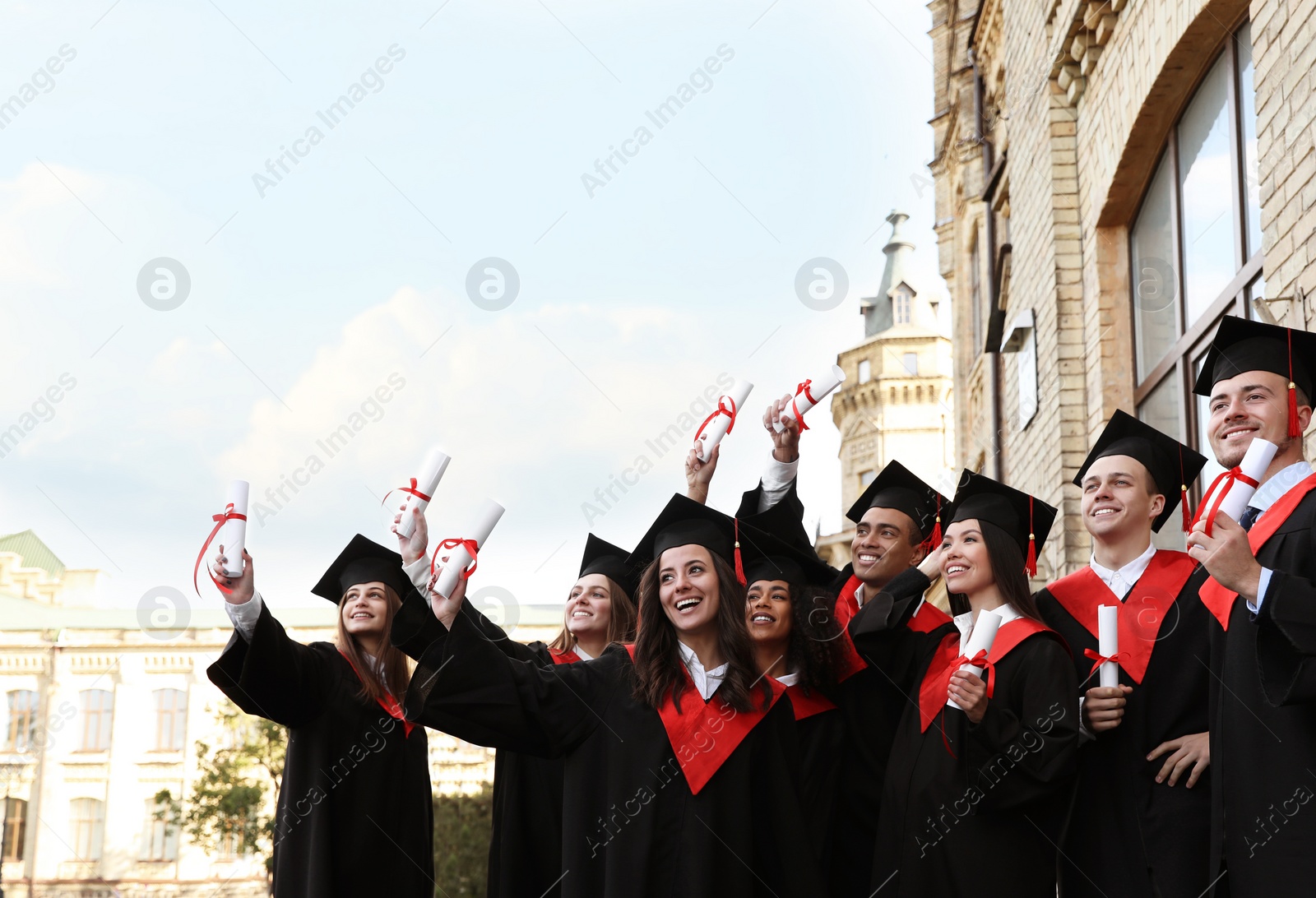 Photo of Happy students with diplomas outdoors. Graduation ceremony