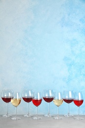 Photo of Glasses with different wine on table against color background