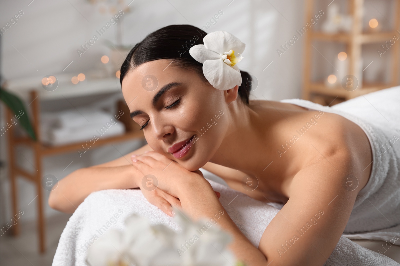 Photo of Beautiful happy woman relaxing on massage table in spa salon