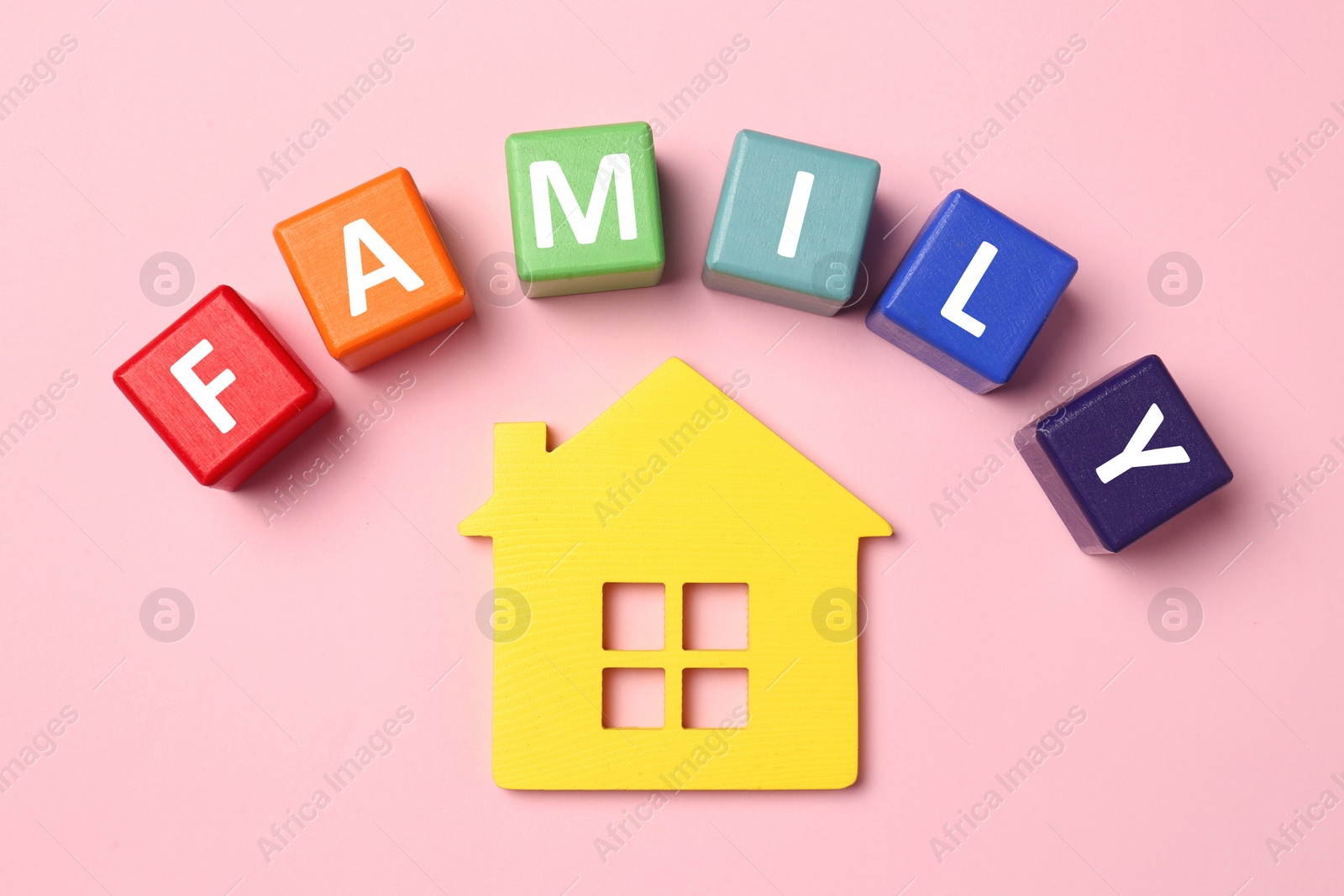 Photo of House figure and word Family made of colorful cubes with letters on pink table, flat lay
