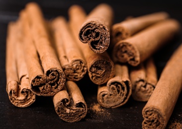 Photo of Aromatic cinnamon sticks and spoon with powder on wooden table, closeup