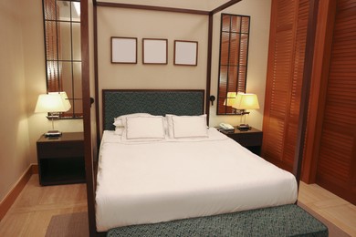 Large bed between bedside tables with lamps in comfortable hotel room