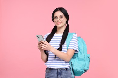 Student with smartphone and backpack on pink background