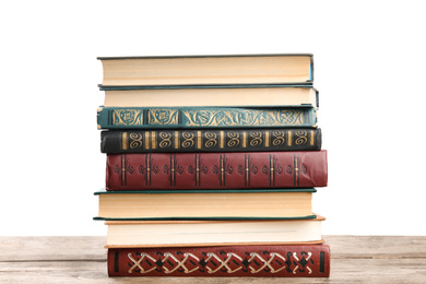 Stack of old vintage books on wooden table against white background