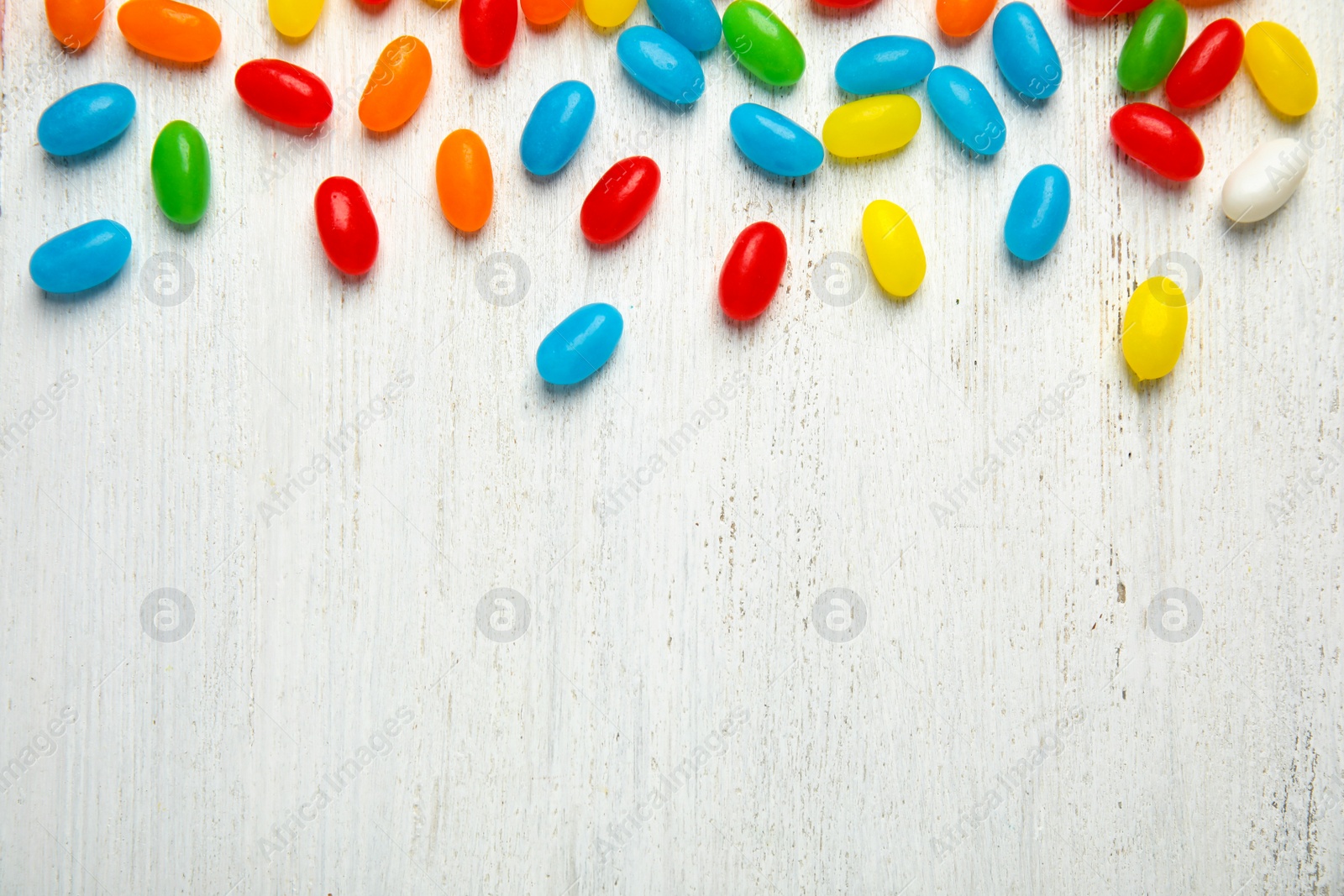 Photo of Flat lay composition with jelly beans on light background. Space for text