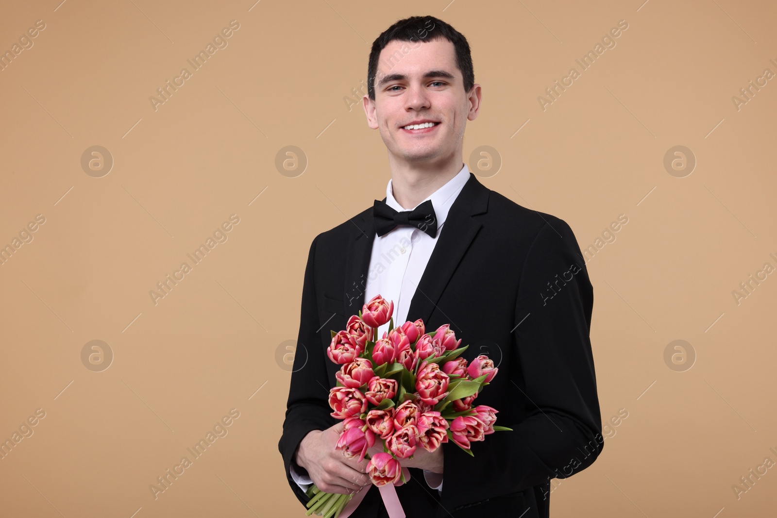 Photo of Happy young man with beautiful bouquet on beige background