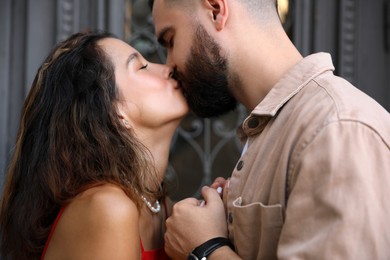 Photo of Happy young couple kissing near door outdoors, closeup