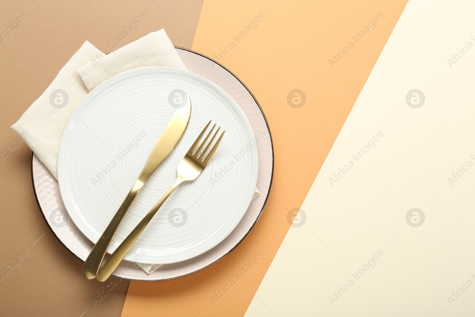 Photo of Ceramic plates, cutlery and napkin on color background, top view. Space for text