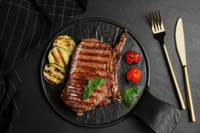 Flat lay composition with grilled meat steak on black table