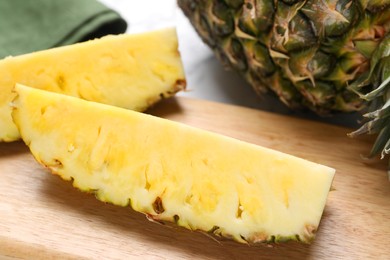 Photo of Wooden board with cut tasty ripe pineapple on table, closeup