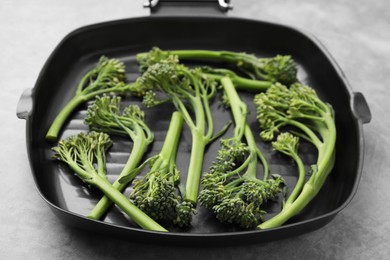 Photo of Pan with fresh raw broccolini on light grey table, closeup. Healthy food