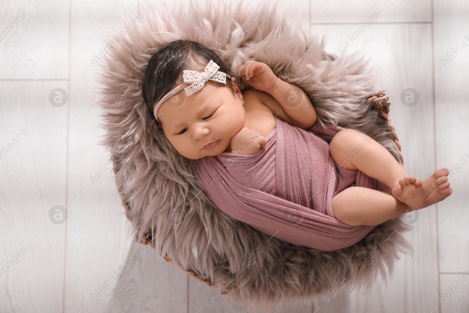 Photo of Cute newborn baby lying in wicker basket, top view