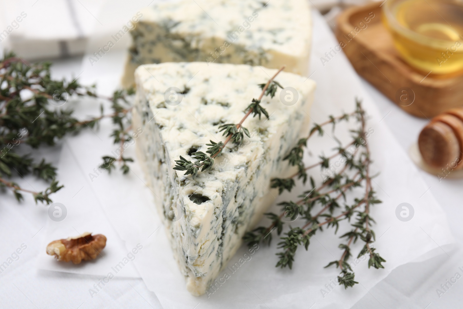 Photo of Tasty blue cheese with thyme on white table, closeup