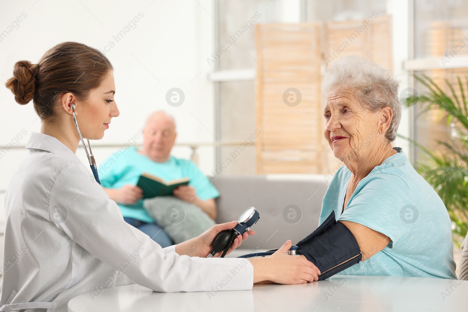 Photo of Nurse measuring blood pressure of elderly woman indoors. Assisting senior generation