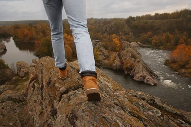 Photo of Man wearing stylish hiking boots on steep cliff, closeup