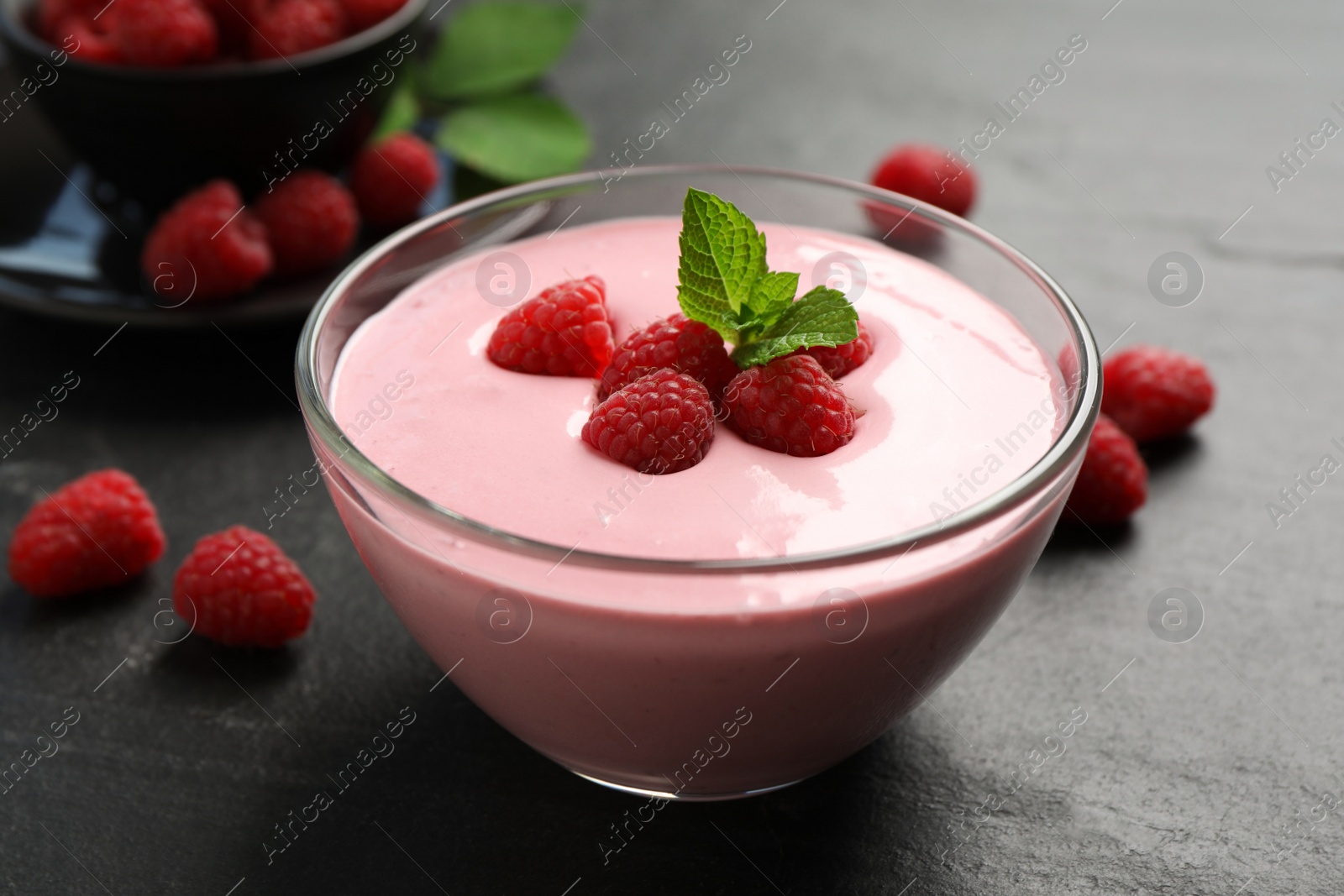 Photo of Delicious raspberry mousse with mint on black table