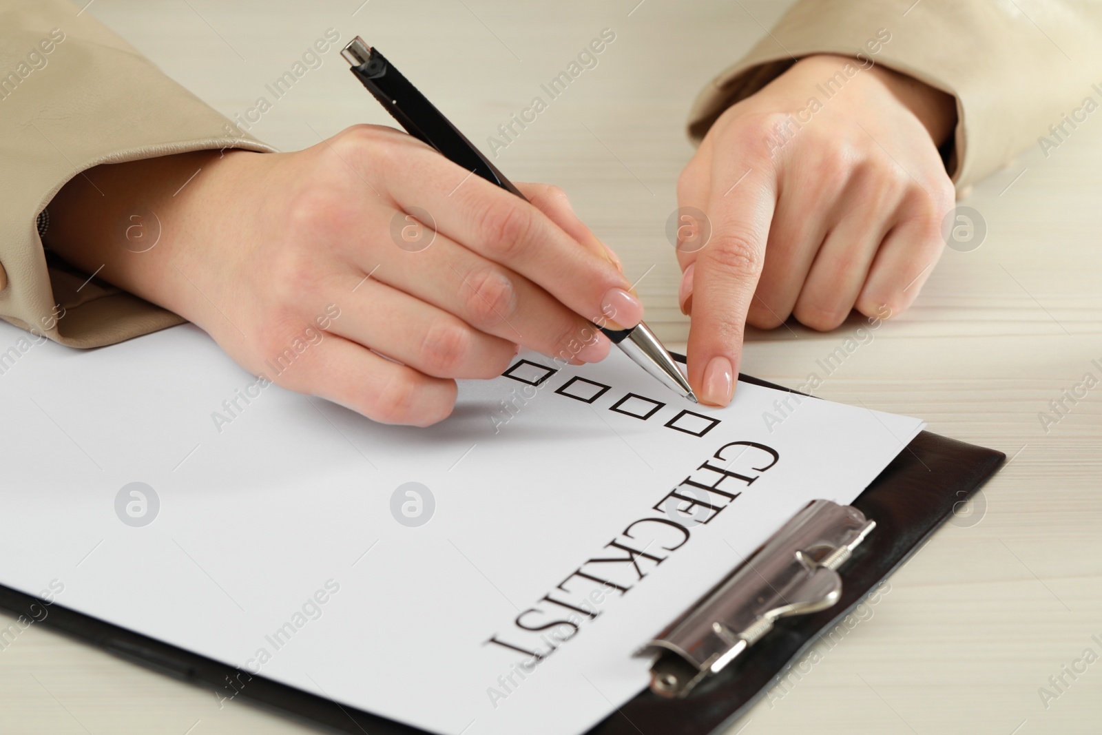 Photo of Woman filling Checklist at white wooden table, closeup