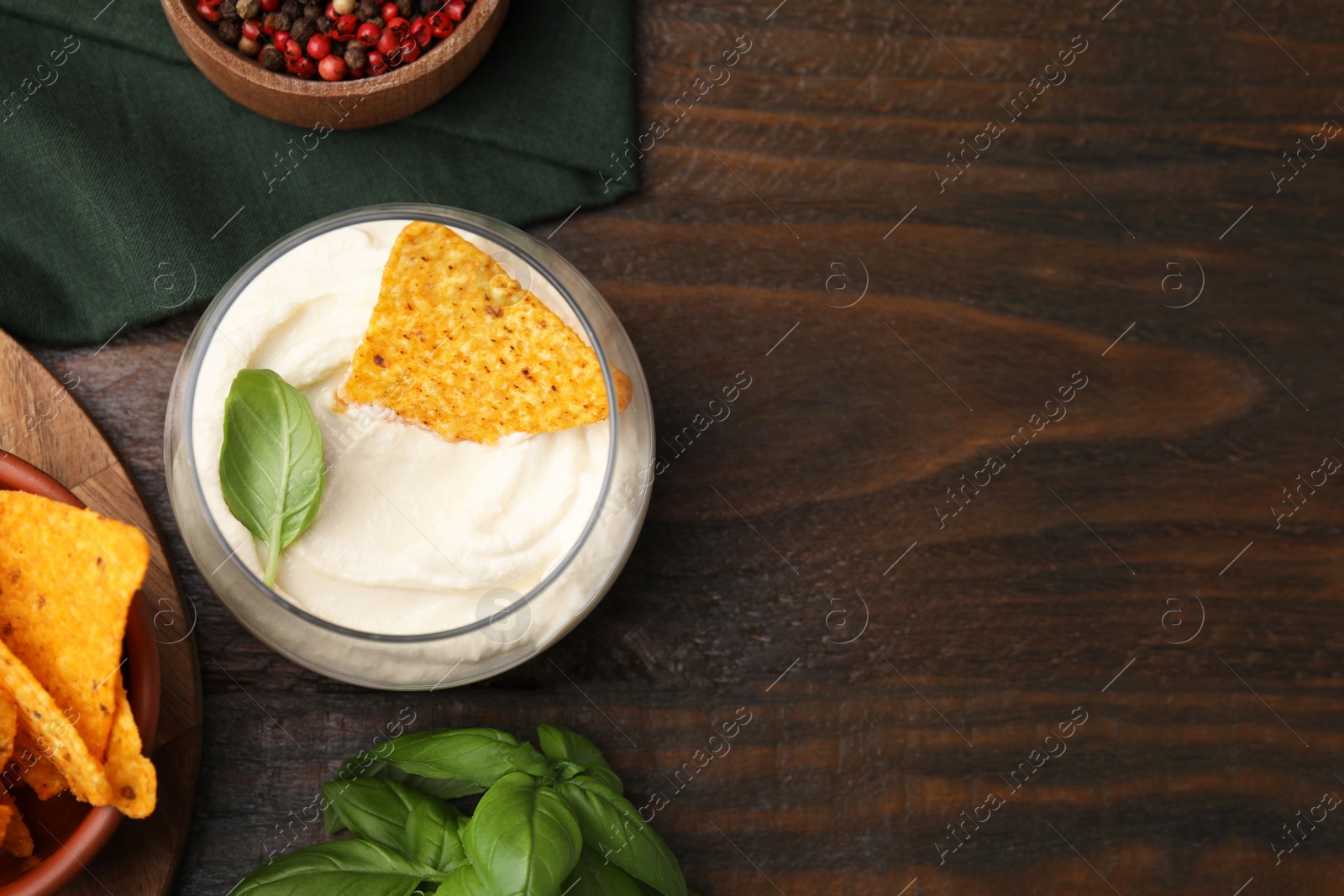 Photo of Delicious tofu sauce served with nachos chip on wooden table, flat lay. Space for text