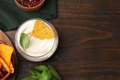 Delicious tofu sauce served with nachos chip on wooden table, flat lay. Space for text