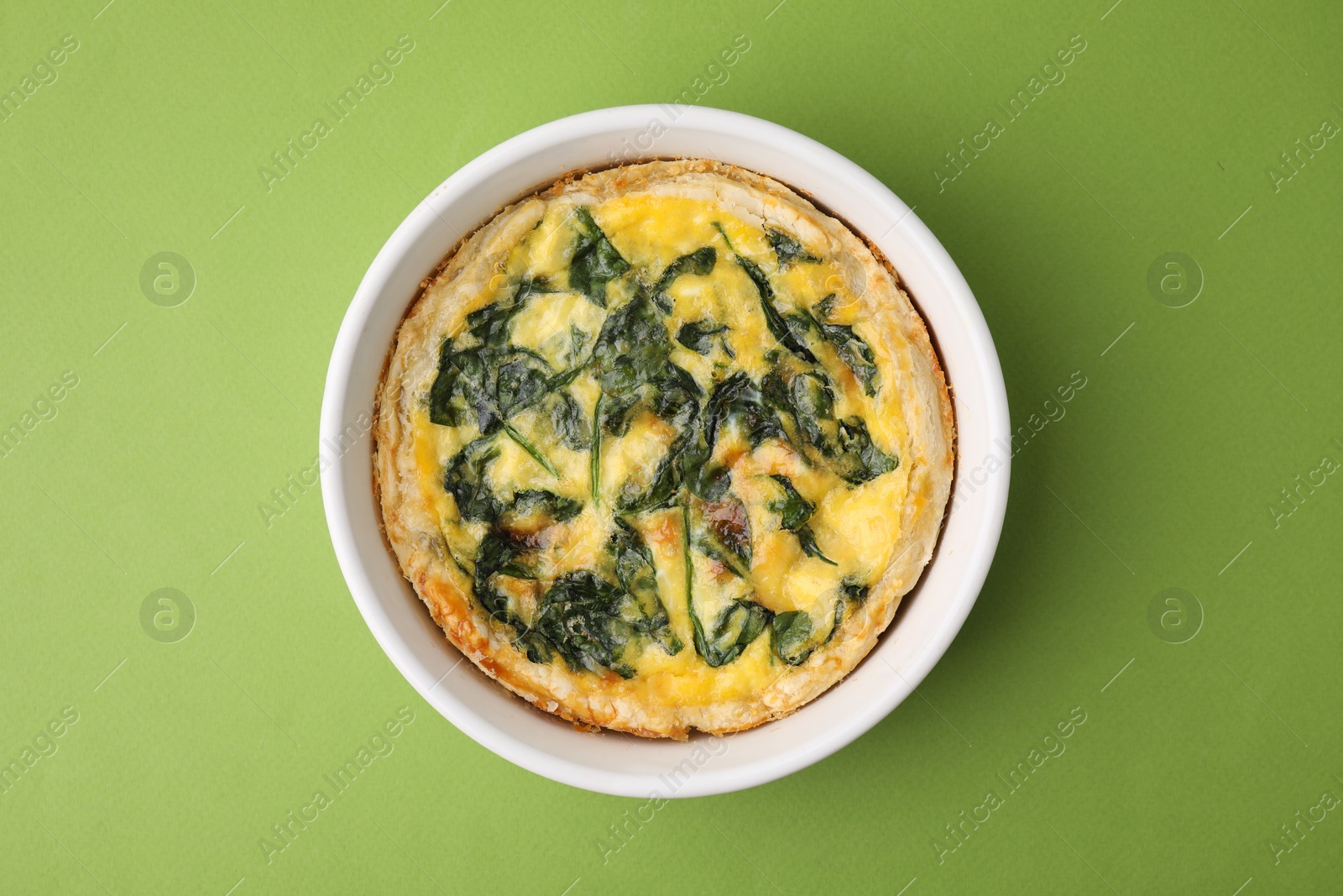 Photo of Delicious pie with spinach on green background, top view