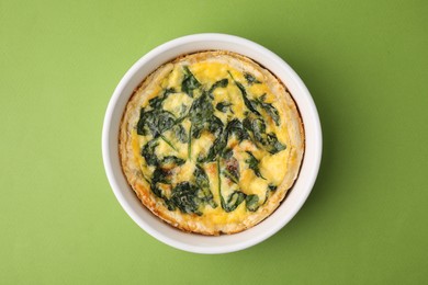 Photo of Delicious pie with spinach on green background, top view