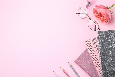 Flat lay composition with notebooks and flower on pink background. Space for text