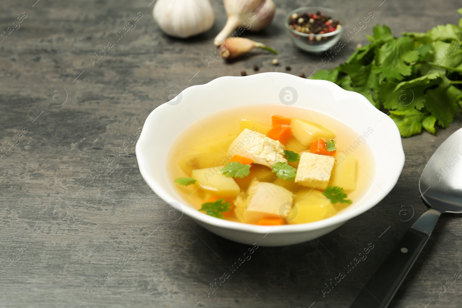 Photo of Dish with fresh homemade chicken soup on grey table, space for text